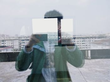 Man standing in city against sky