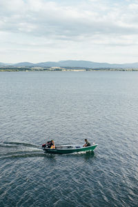 People on boat in sea against sky