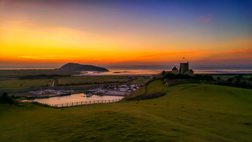 Harbor and church by sea against sky at sunset