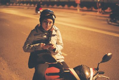 Portrait of woman using mobile phone while sitting on motorcycle over road