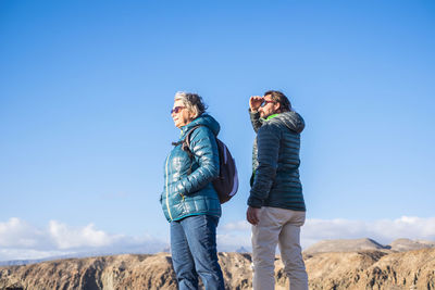 Mother and son standing against sky during sunny day