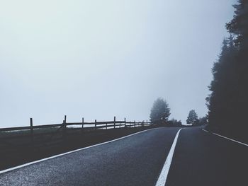 Road amidst trees against clear sky