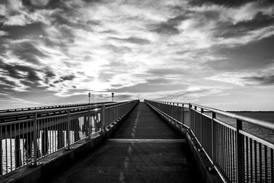 Pier on sea against cloudy sky