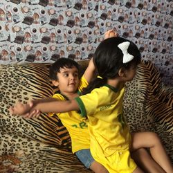 Siblings playing on sofa at home