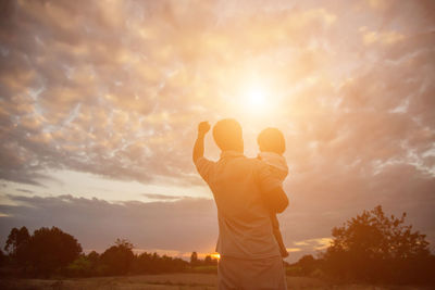 Rear view of man standing against sky during sunset