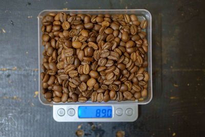 Close-up of roasted coffee beans in weight scale on table