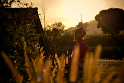 Woman on field against sky during sunset