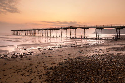 Pier over sea against sky during sunset