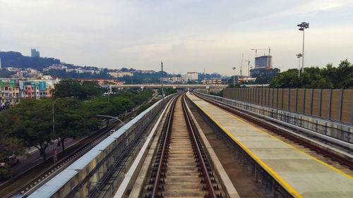 Railroad tracks in city against sky