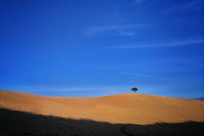 Scenic view of desert against blue sky