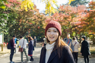 Portrait of smiling young woman against trees