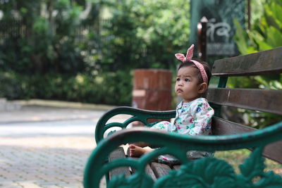 Baby girl sitting on bench at park