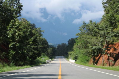 Empty road amidst trees against sky