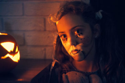 Cute girl wearing costume standing by pumpkin during halloween