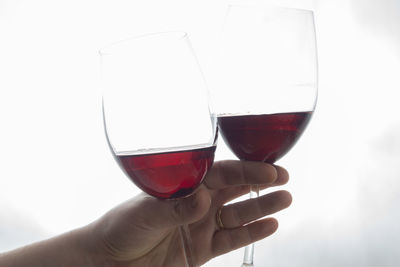 Close-up of woman holding wineglass against white background