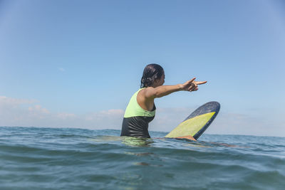 Female surfer sitting on surfboard