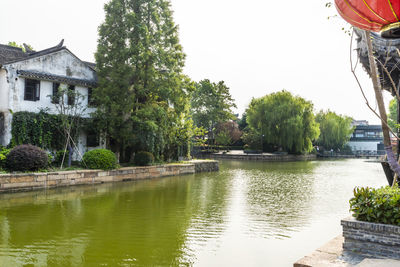 Scenic view of lake by trees and building against sky