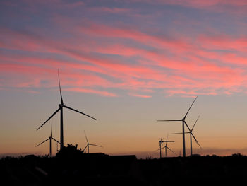 Silhouette windmills against sky during sunset