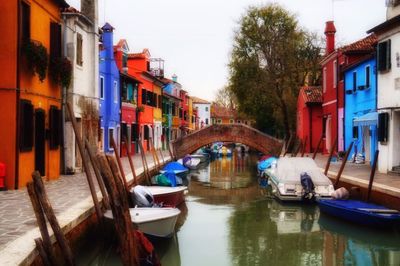 Boats moored in canal amidst buildings in city