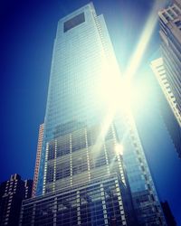 Low angle view of skyscrapers against bright sun