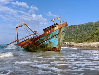 Abandoned ship in sea against sky