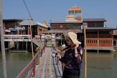 Woman standing by building against sky