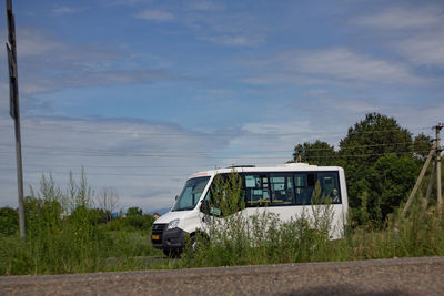 Car on road amidst field against sky