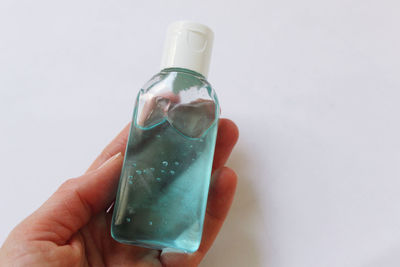 Close-up of hand holding bottle against white background