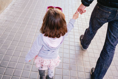 Father and toddler daughter walking down the street holding hands