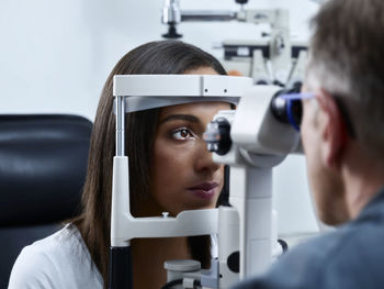 Optometrist examining young woman's eye