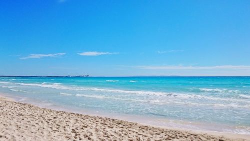 Scenic view of beach against clear blue sky