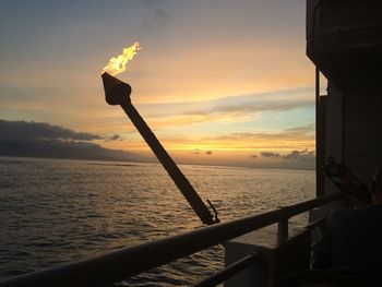 Silhouette railing by sea against sky during sunset