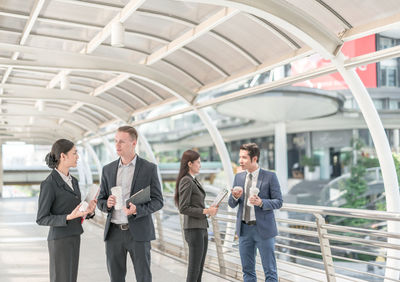 Business people discussing while standing on elevated walkway