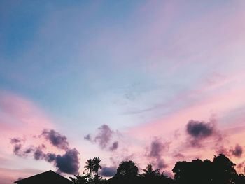 Low angle view of silhouette trees against dramatic sky