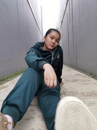 Full length of woman sitting against wall