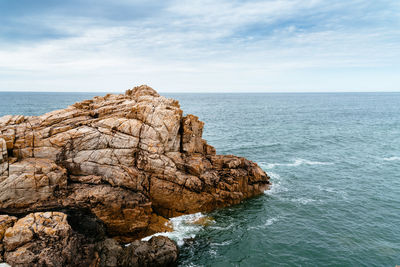 Rock formation in sea against sky