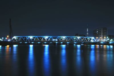 Illuminated bridge over river against sky at night