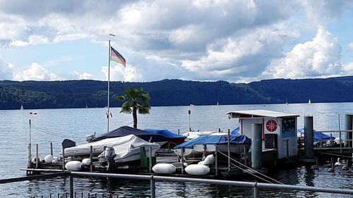 Boats moored on sea by mountains against sky