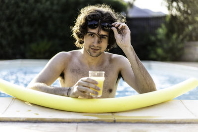 Portrait of young man sitting in swimming pool