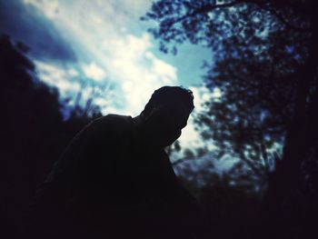 Low angle view of silhouette person on rock against sky