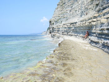 Woman sitting on rock formation at beach