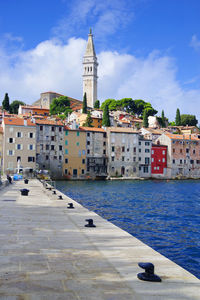 View of buildings by canal against sky in city