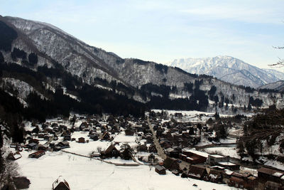 High angle view of townscape and snowcapped mountains against sky