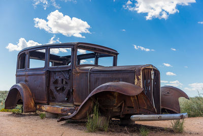 A weathered and rusting studebaker antique car sitting along the old route 66 highway.