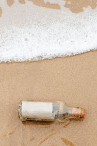 High angle view of empty glass bottle on shore