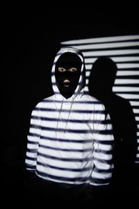 Portrait of man standing against black background