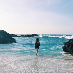 Woman standing at beach against sky