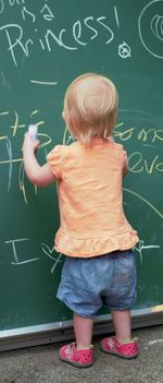 Rear view of baby girl writing on board