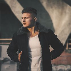 Handsome young man wearing jacket against building