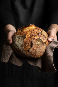 Unrecognizable crop chef in apron standing with piece of freshly baked bread